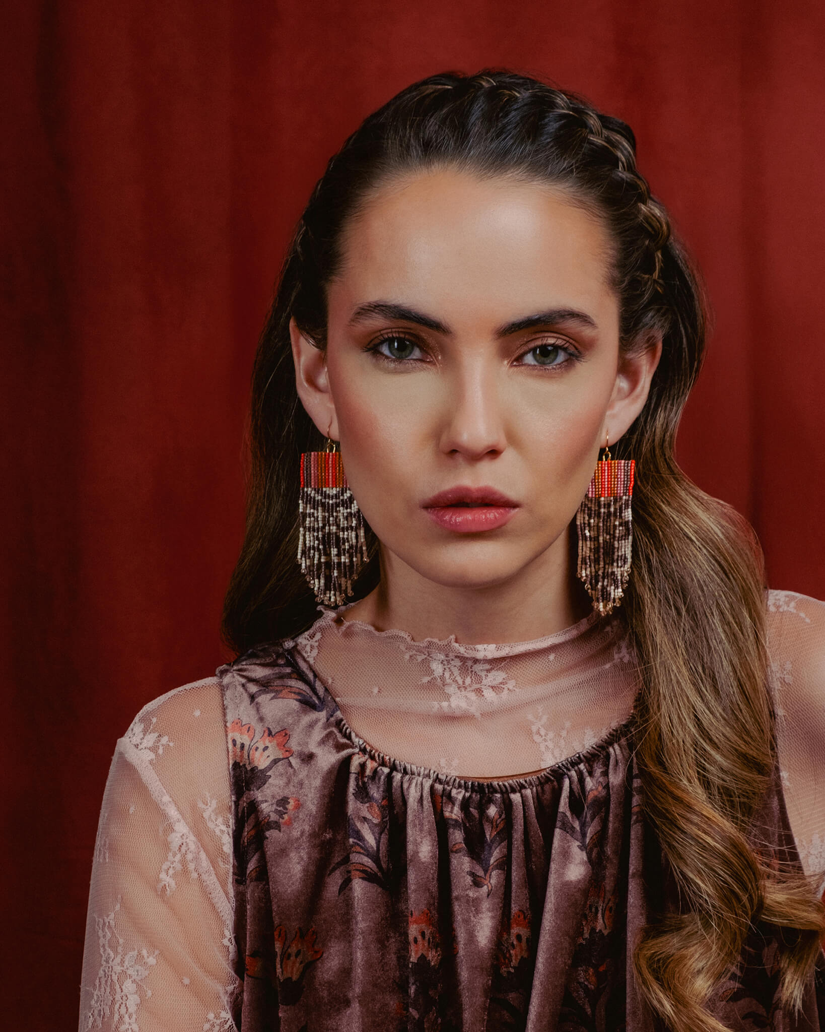 Woman wearing large earrings against a red background