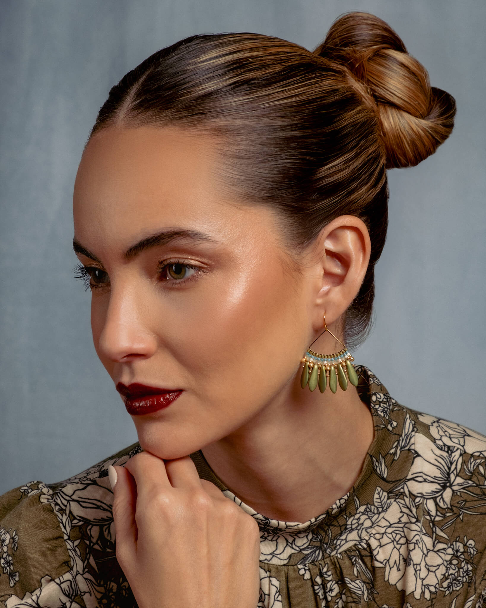 Woman with styled hair and earrings against a gray background