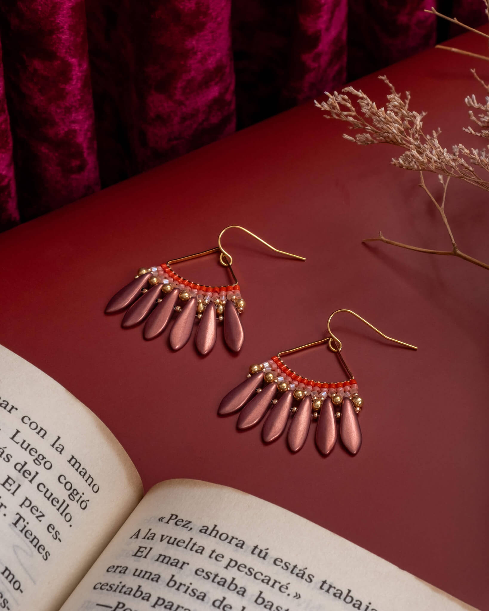 Decorative earrings on an open book with a red background
