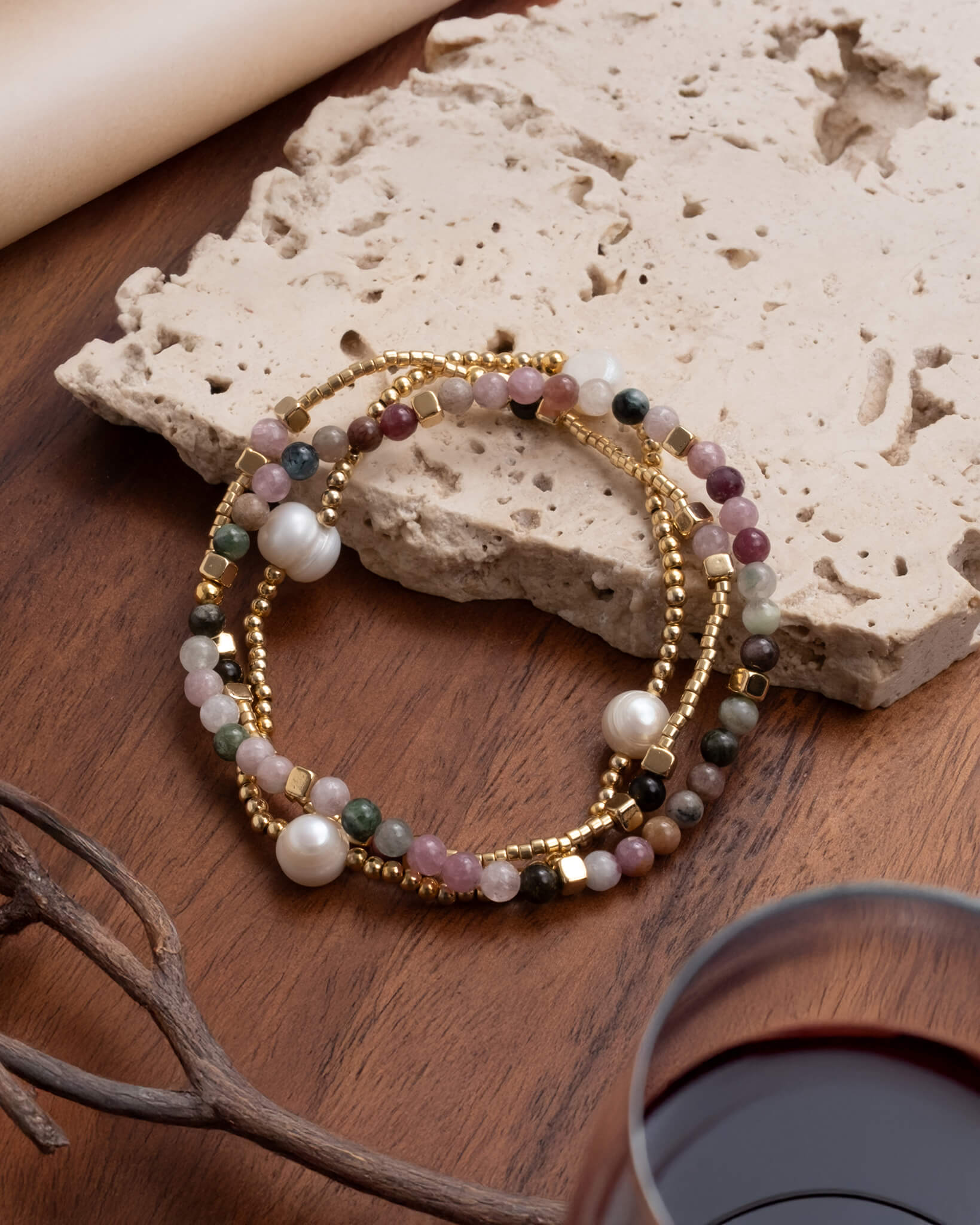 Set of beaded bracelets on a wooden surface with a stone background