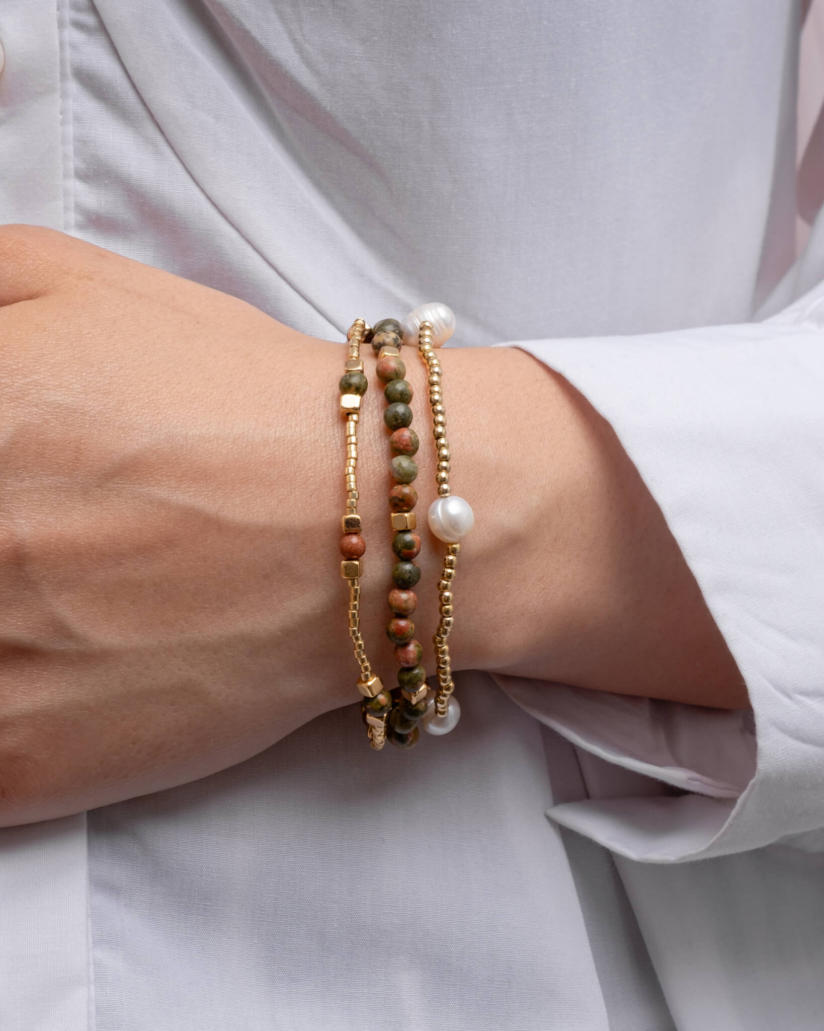 Close-up of a wrist wearing multiple beaded bracelets on a light background